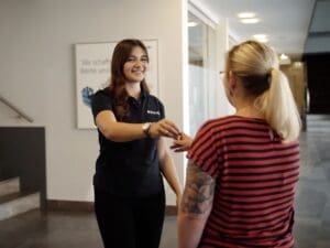 Bild: © Push it! Eine Auszubildende überreicht einer Frau einen Wohnungsschlüssel.