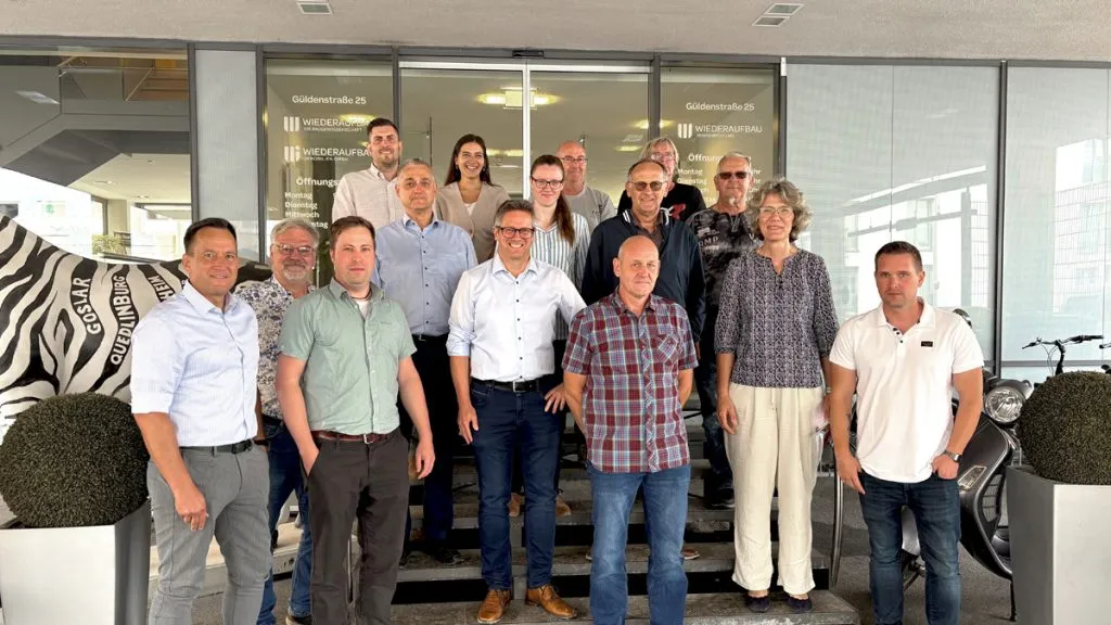 Bild: © WIEDERAUFBAU 15 Personen stehen auf der Treppe zum Eingang der Baugenossenschaft Wiederaufbau eG.