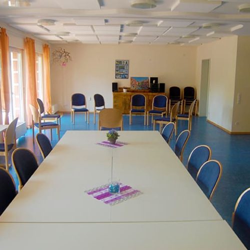 Bild: © WIEDERAUFBAU Gemeinschaftsraum mit Tischen und Stühlen und großer Fensterfront des Betreuten Wohnen Volkmarode.