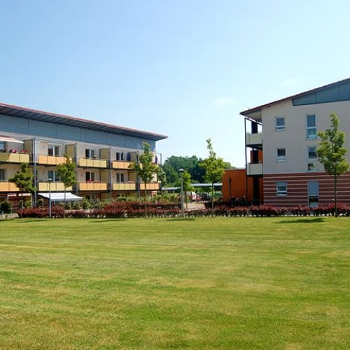 Bild: © WIEDERAUFBAU Blick von einer Wiese auf das mehrstöckige Betreute Wohnen mit Balkonen in Volkmarode.