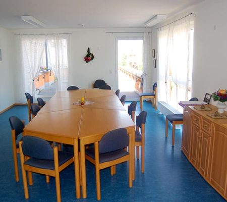 Bild: © WIEDERAUFBAU Gemeinschaftsraum mit großem Tisch und Stühlen und Zugang zu einer Terrasse des Betreuten Wohnen Volkmarode.