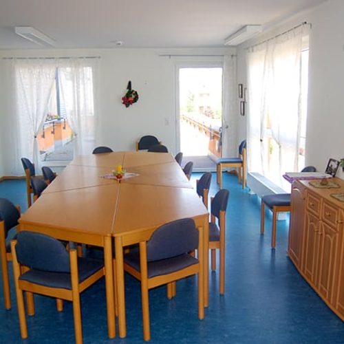 Bild: © WIEDERAUFBAU Gemeinschaftsraum mit großem Tisch und Stühlen und Zugang zu einer Terrasse des Betreuten Wohnen Volkmarode.