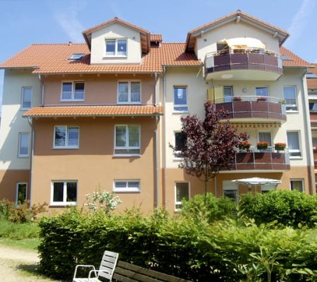 Bild: © WIEDERAUFBAU Blick von der Grünflächen auf das mehrstöckige Betreute Wohnen in Querum mit Balkonen.