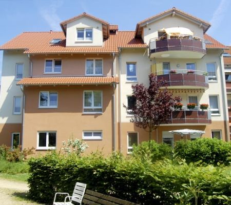 Bild: © WIEDERAUFBAU Blick von der Grünflächen auf das mehrstöckige Betreute Wohnen in Querum mit Balkonen.