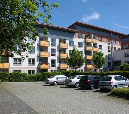 Bild: © WEDERAUFBAU Mehrstöckiger Wohnkomplex mit Balkonen des Betreuten Wohnens Broitzem und Parkplatz.