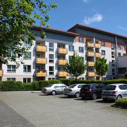 Bild: © WEDERAUFBAU Mehrstöckiger Wohnkomplex mit Balkonen des Betreuten Wohnens Broitzem und Parkplatz.