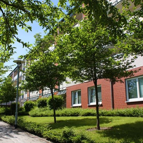 Bild: © WEDERAUFBAU Vor dem mehrstöckiger Wohnkomplex des Betreuten Wohnens Broitzem stehen Bäume.