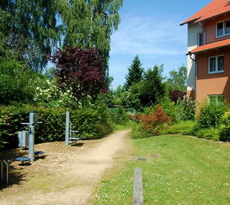 Bild: © WIEDERAUFBAU Bewegungsparcours an einer Wiese vor dem mehrstöckigen Betreuten Wohnen Querum.
