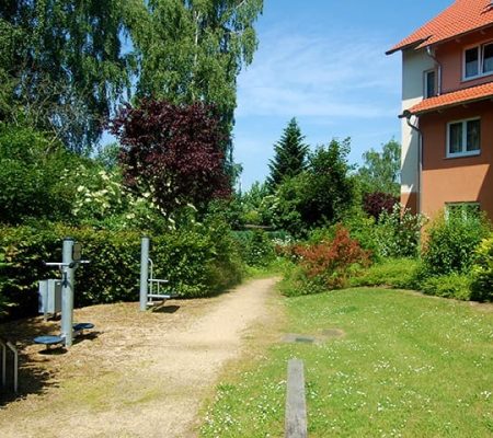 Bild: © WIEDERAUFBAU Bewegungsparcours an einer Wiese vor dem mehrstöckigen Betreuten Wohnen Querum.