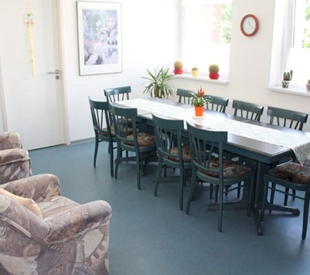 Bild: © WEDERAUFBAU Gemeinschaftsraum mit einem Tisch für 10 Personen und zwei Sesseln im Betreuten Wohnen Juliusstraße.