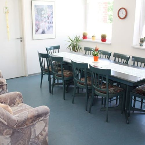 Bild: © WEDERAUFBAU Gemeinschaftsraum mit einem Tisch für 10 Personen und zwei Sesseln im Betreuten Wohnen Juliusstraße.