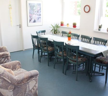 Bild: © WEDERAUFBAU Gemeinschaftsraum mit einem Tisch für 10 Personen und zwei Sesseln im Betreuten Wohnen Juliusstraße.