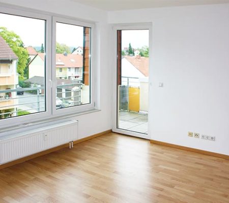 Bild: © WIEDERAUFBAU Beispiel eines Wohnzimmers im Betreuten Wohnen Goslars mit Balkon und hellbraunen Bodenbelag.