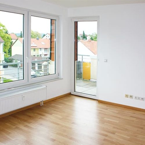 Bild: © WIEDERAUFBAU Beispiel eines Wohnzimmers im Betreuten Wohnen Goslars mit Balkon und hellbraunen Bodenbelag.