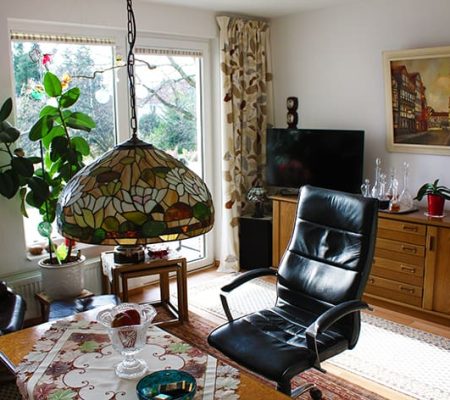 Bild: © WIEDERAUFBAU Beispiel eines Wohnzimmers mit großen Fenster, Balkon und hellbraunen Bodenbelage im Betreuten Wohnen Querum.