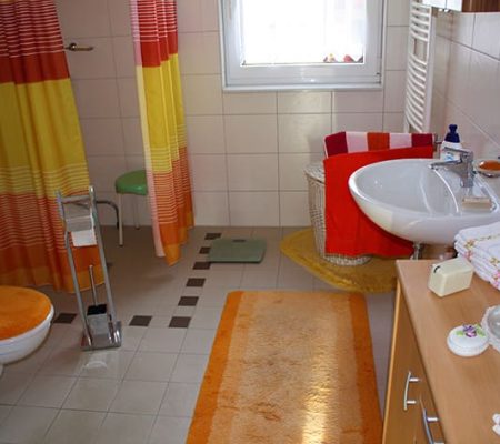Bild: © WIEDERAUFBAU Beispiel eines Badezimmers mit bodengleicher Dusche, Fenster weißen Wandfliesen und grauen Bodenfliesen im Betreuten Wohnen Querum.
