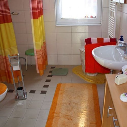 Bild: © WIEDERAUFBAU Beispiel eines Badezimmers mit bodengleicher Dusche, Fenster weißen Wandfliesen und grauen Bodenfliesen im Betreuten Wohnen Querum.