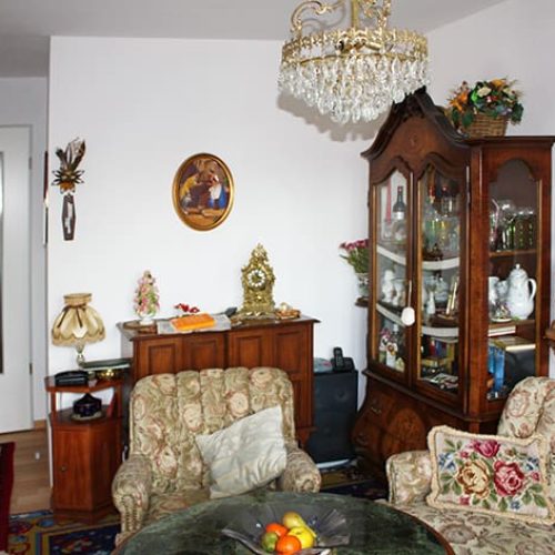 Bild: © WIEDERAUFBAU Beispiel eines Wohnzimmers mit weißen Wänden und hellbraunen Bodenbelag im Betreuten Wohnen Querum.