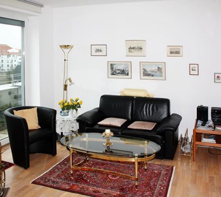 Bild: © WEDERAUFBAU Ein Wohnzimmer mit bodentiefem Fenster und hellem Bodenbelag in der Juliusstraße.