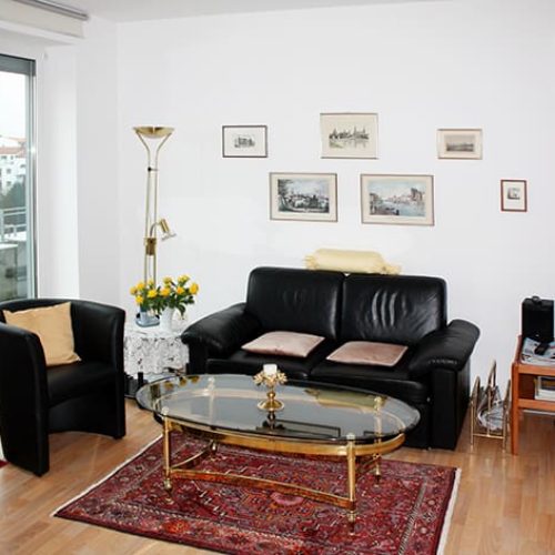 Bild: © WEDERAUFBAU Ein Wohnzimmer mit bodentiefem Fenster und hellem Bodenbelag in der Juliusstraße.