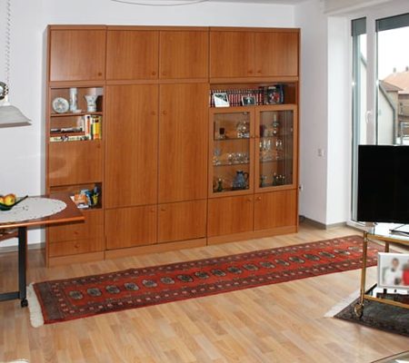 Bild: © WEDERAUFBAU Ein Wohnzimmer im Betreuten Wohnen Juliusstraße mit bodentiefem Fenster und hellem Bodenbelag.