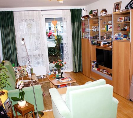 Bild: © WIEDERAUFBAU Beispiel eines Wohnzimmers mit Terrasse und hellbraunen Bodenbelag im Betreuten Wohnen Volkmarode.
