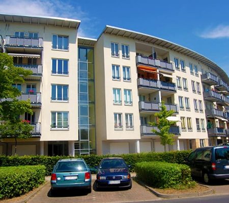 Bild: © WIEDERAUFBAU Die rundliche Außenansicht des 5-stöckigen Wohngebäudes mit Balkonen und Parkplätzen des Betreuten Wohnen Braunschweig-Weststadt.