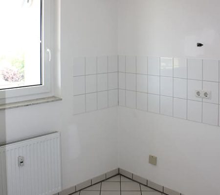 Bild: © WEDERAUFBAU Die Küchenzeile mit weißem Fliesenspiegel und weißen Bodenfliesen in Broitzem.