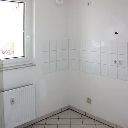 Bild: © WEDERAUFBAU Die Küchenzeile mit weißem Fliesenspiegel und weißen Bodenfliesen in Broitzem.